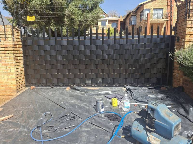 Gate weaving in progress: steel slats being woven through an existing gate